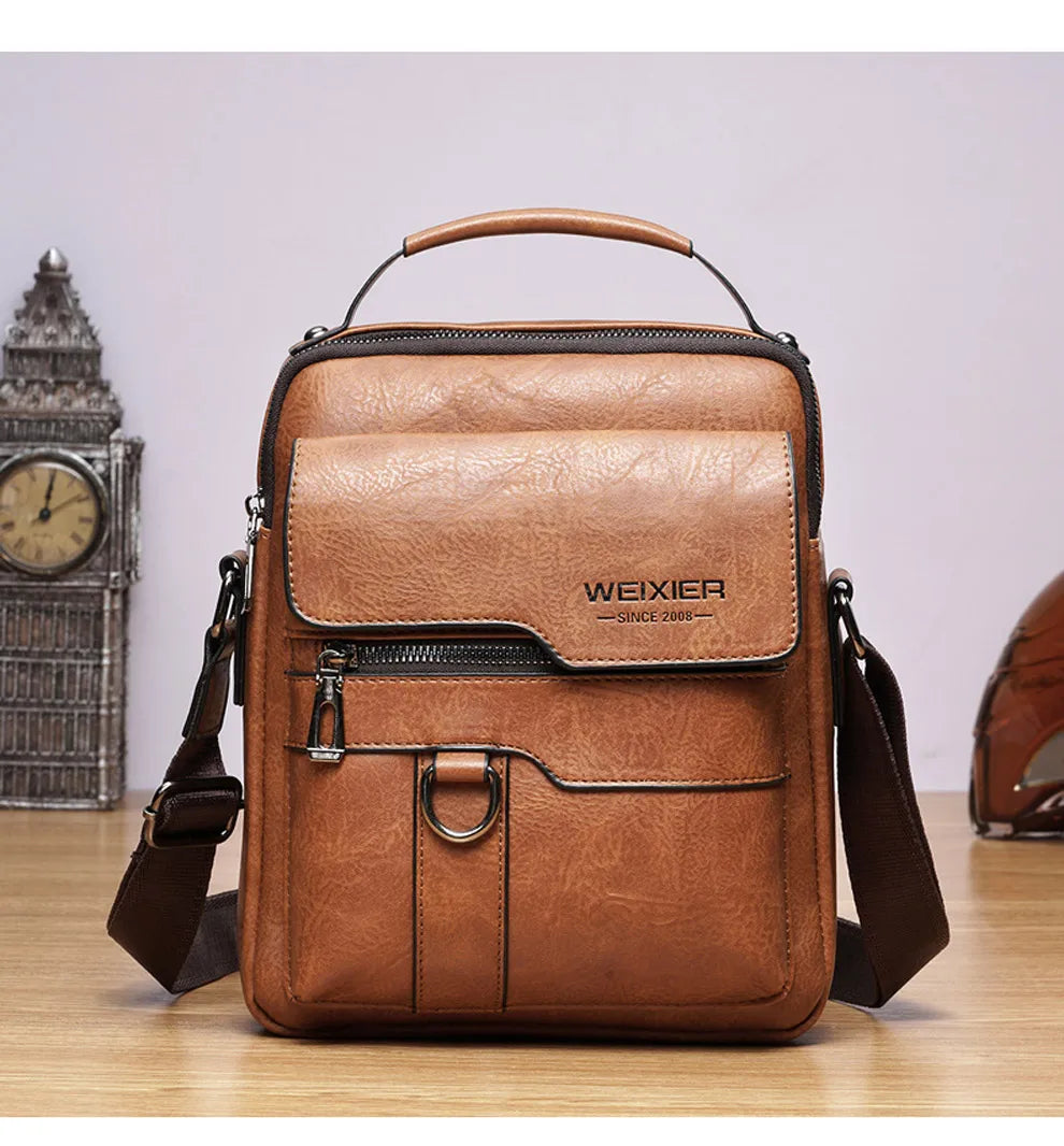 A brown vintage PU leather crossbody messenger bag with a leather handle and flap resting on a wooden surface.
