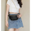 A woman wearing a white cropped top and denim skirt holds a black PU leather crossbody sling bag.