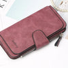 A mauve PU leather card holder wallet with a zipper and a decorative flap resting on white paper.