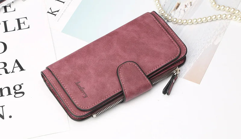 A mauve PU leather card holder wallet with a zipper and a decorative flap resting on white paper.