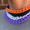 A close-up of a layered necklace featuring acrylic link chains in orange, black, white, and purple.