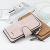 A pink leather card holder wallet next to a perfume bottle and pearl necklace on a white background.