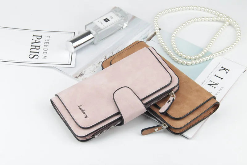 A pink leather card holder wallet next to a perfume bottle and pearl necklace on a white background.