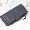 A dark blue leather card holder wallet lying on a white surface next to some papers and a pearl necklace.