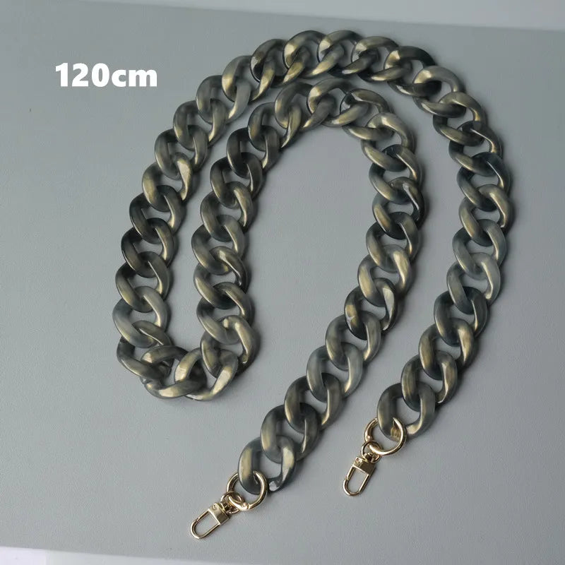Bolso de cadena de hombro de resina plateada mostrado contra un fondo gris, con referencia de escala de 120 cm.