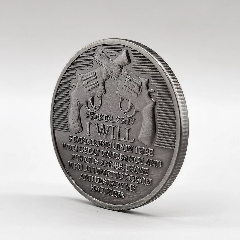 A silver-plated commemorative coin featuring a depiction of a gun and the text I WILL STRIKE DOWN UPON THEE WITH GREAT VENGEA