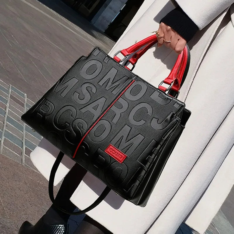 Sac bandoulière en cuir PU noir avec accents rouges porté par une personne en extérieur.