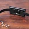Porte-clés pour téléphone en cuir noir posé sur une surface en bois foncé.
