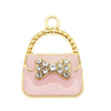 Charm à sac ton or, boucle et corps en émail rose décoré d'un amas de cristaux clairs.