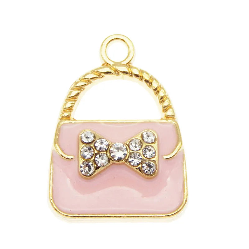 Charm à sac ton or, boucle et corps en émail rose décoré d'un amas de cristaux clairs.