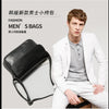 A male model wearing a white blazer and trousers posing with a black PU leather crossbody bag.