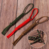 A set of three paracord keychains and utility ropes in green, red, and brown on a wooden surface.