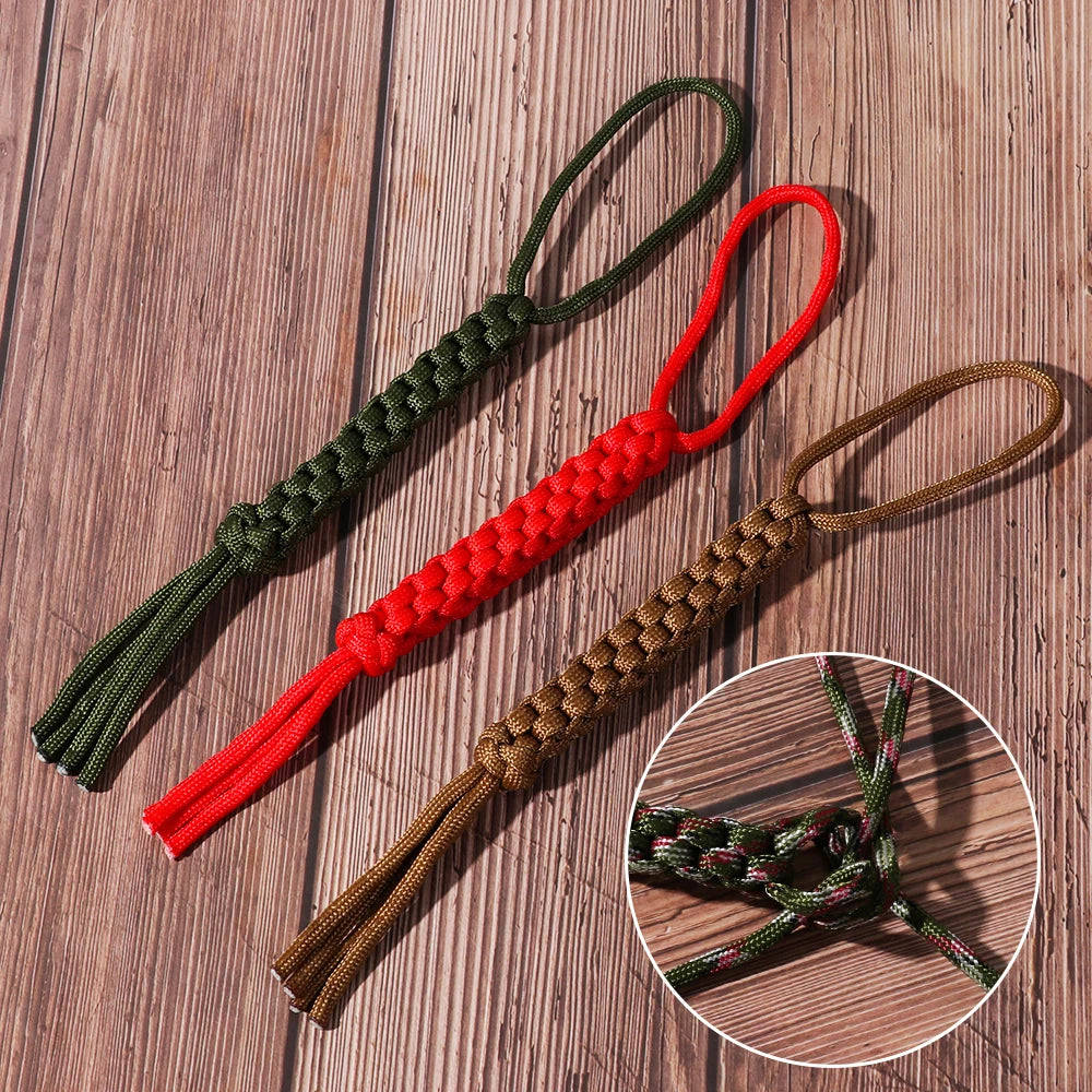 A set of three paracord keychains and utility ropes in green, red, and brown on a wooden surface.