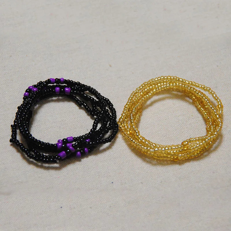 Two strands of colorful belly bead chains, one black and purple, and one yellow.