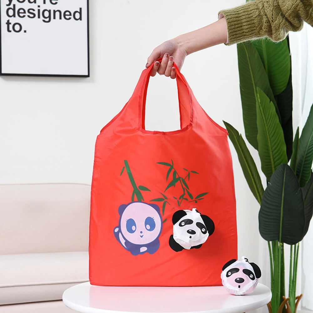 Un sac de shopping rouge vif avec des illustrations de pandas, tenu par une main à côté d'une grande plante verte.