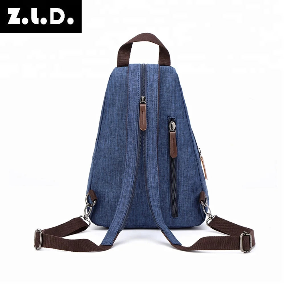 A dark blue canvas backpack with brown leather straps and zippers, shown from the back.