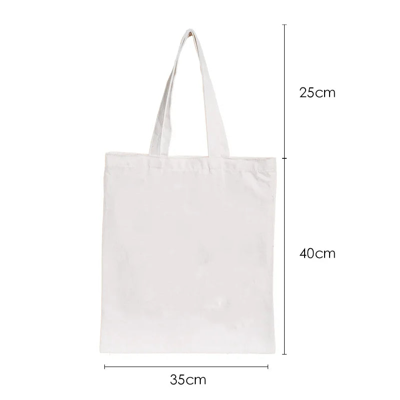 White canvas tote bag with a ghost and pumpkin print, shown from the side.