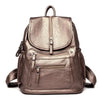 A brown vintage soft leather backpack with a flap and zippered pockets.