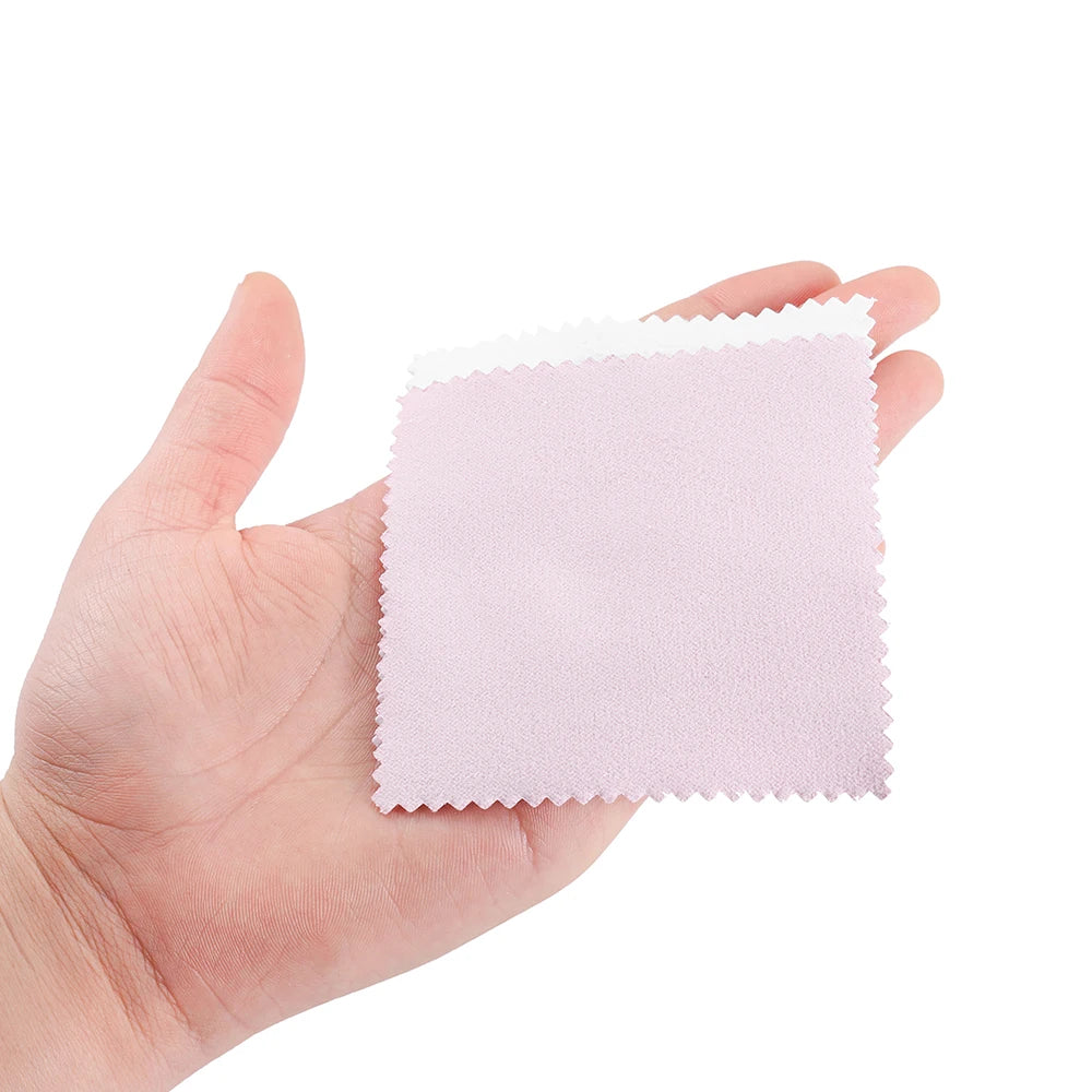 A hand holds a square pink polishing cloth made of felt or microfiber.