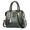 A dark green crocodile-embossed leather tassel shoulder bag with gold hardware.