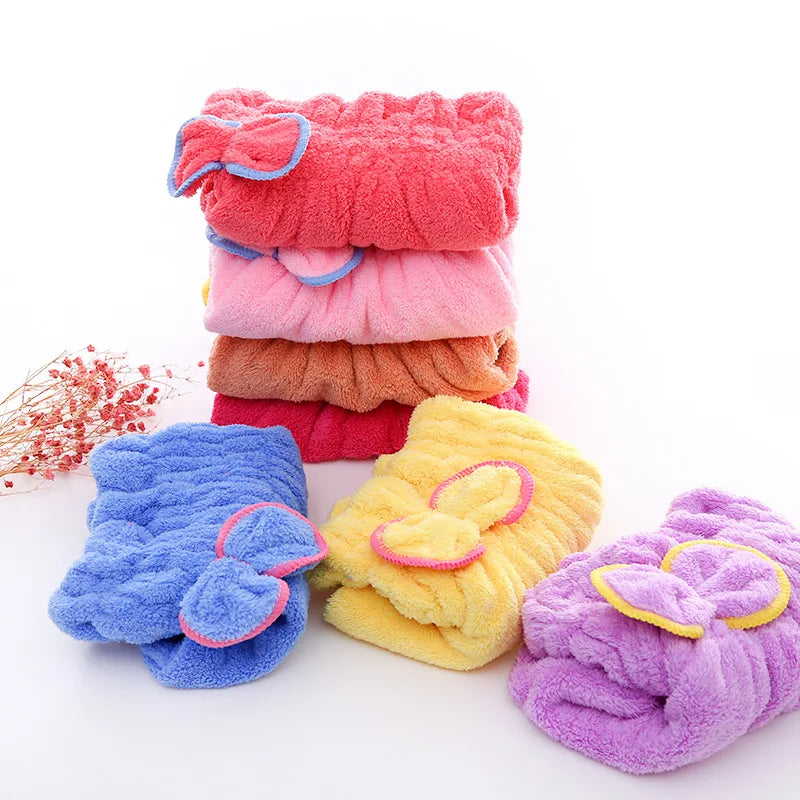 Una pila de toallas y pañuelos de cabello de microfibra coloridos en tonos rosa, naranja y morado.