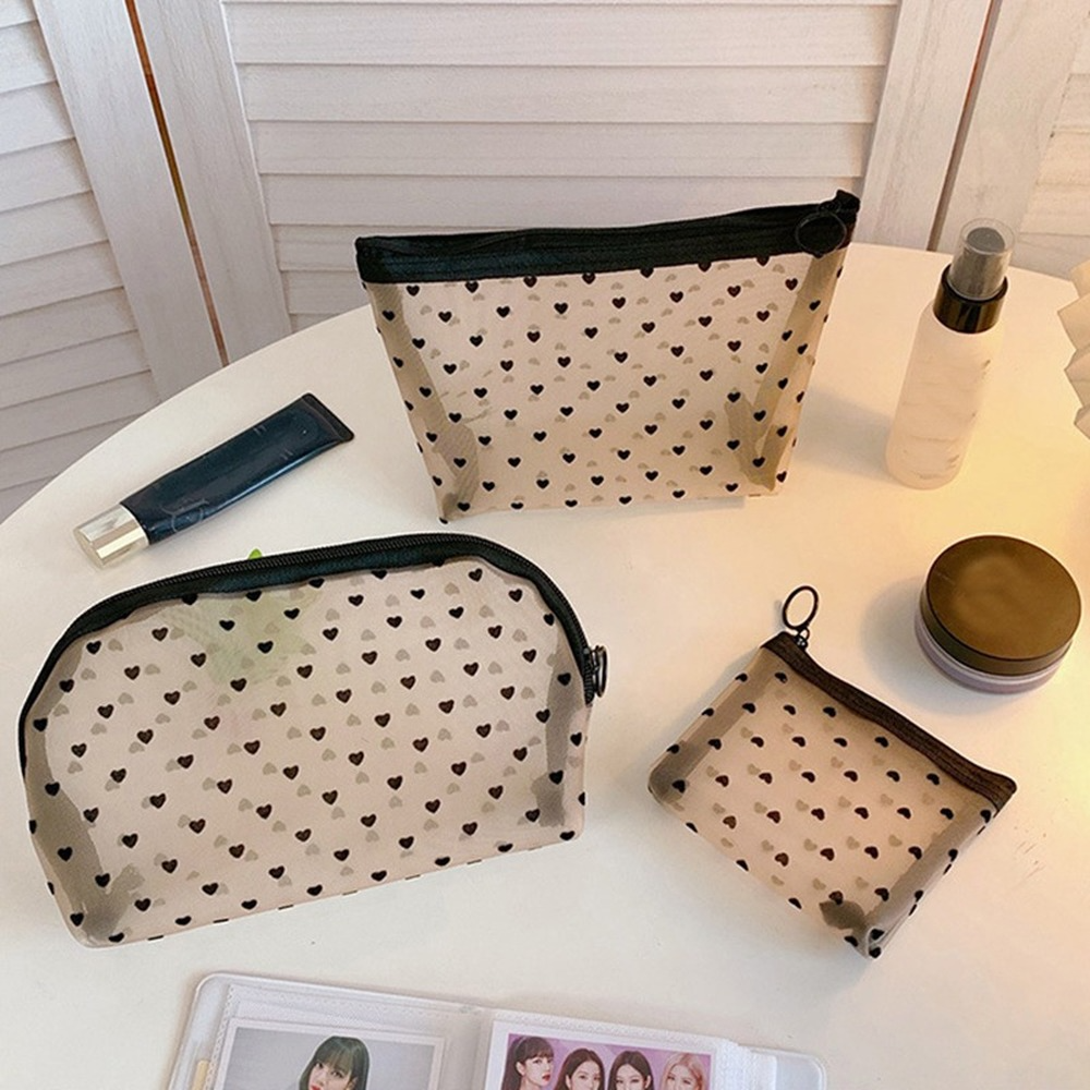 A beige mesh cosmetic storage pouch is displayed on a white surface next to a bottle and other small items.