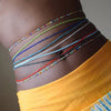 Colorful belly bead chains with various colored threads draped across the abdomen.