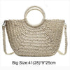 Handwoven straw moon bag with a top handle in a natural beige color.