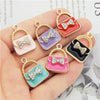 Un ensemble de six charms en alliage émail de cristal aux couleurs et designs variés, présentés sur une main.