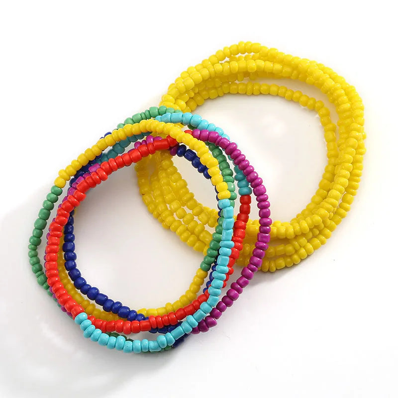 A collection of colorful belly bead chains featuring yellow, pink, blue, and green beads.