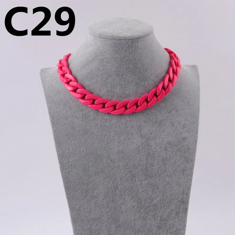 A close-up of a bright pink acrylic link chain necklace displayed on a gray mannequin neck.