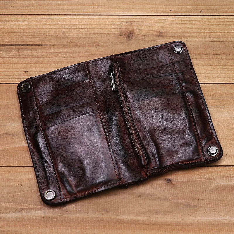 Dunkelbraunes Leder-Bifold-Portemonnaie mit gestickten Linien und Metallnieten auf einer Holzoberfläche.