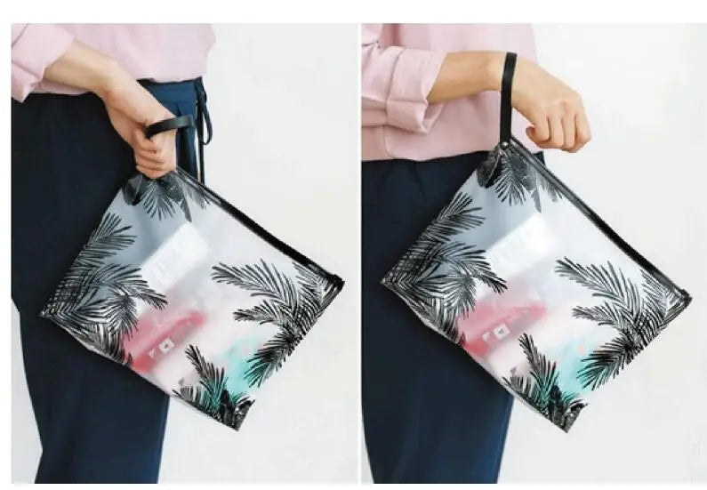Una persona sostiene una bolsa de cosméticos transparente con estampado de hoja tropical.