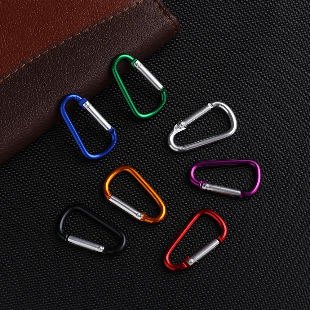 A collection of colorful aluminum carabiner hooks arranged on a dark surface.