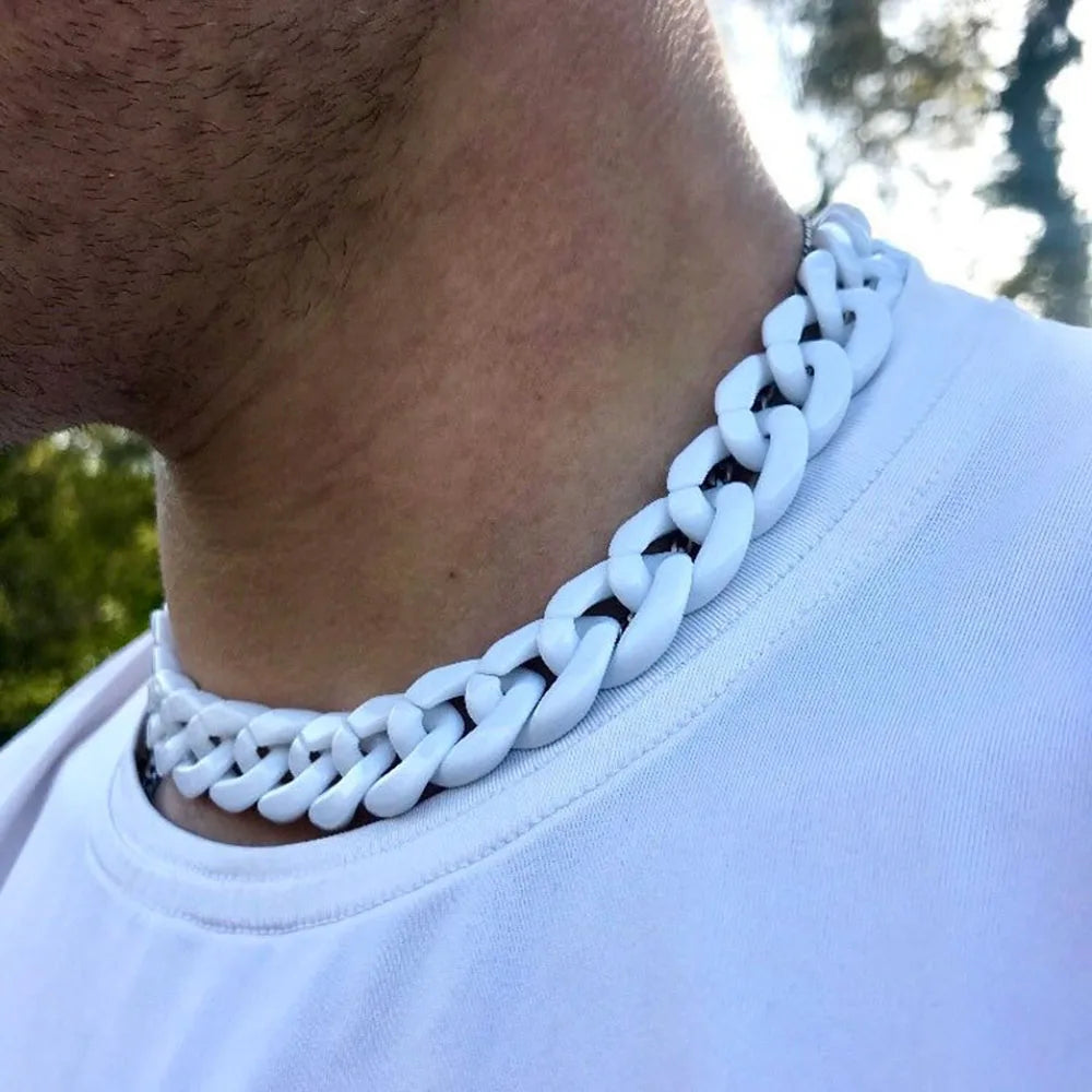 A close-up of a white braided acrylic link chain necklace worn around the neck against a white t-shirt.