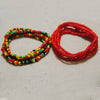 Two strands of colorful belly bead chains, one green and yellow, and one red, laid out on a light surface.