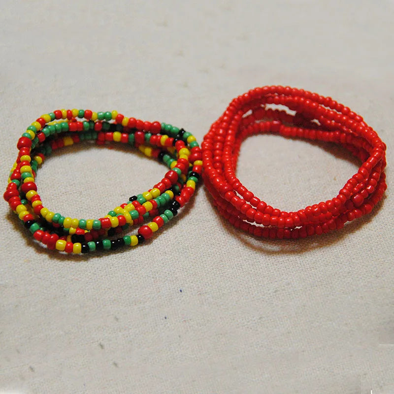 Two strands of colorful belly bead chains, one green and yellow, and one red, laid out on a light surface.