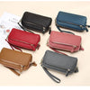 A collection of genuine cowhide leather double-zip wristlet wallets in various colors including black, navy blue, red, and br