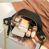 A black PU leather crossbody sling bag filled with perfume bottles and a white card, resting on a beige fabric.