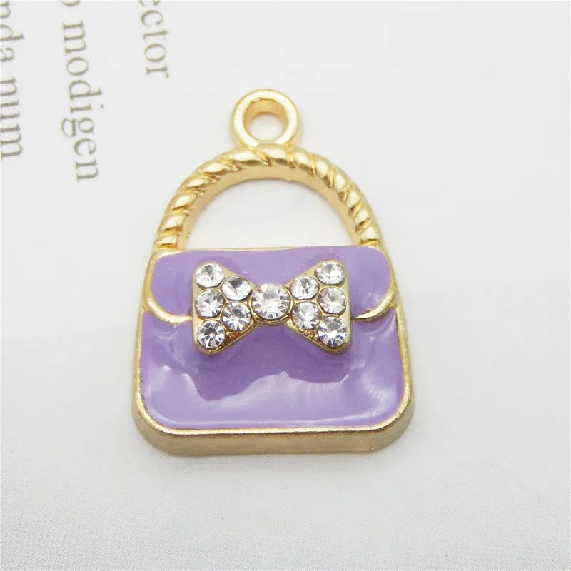 Charm à sac ton or avec corps en émail lavande et nœud scintillant.