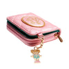 Portefeuille à pièces rose matelassé pour femme avec rabat ovale bordé d'or et un charm en forme de personne.