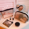 A collection of clear mesh cosmetic storage pouches and a black jar are displayed on a white surface.