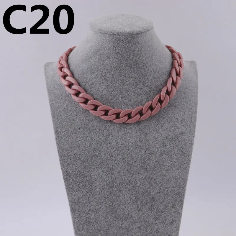 A close-up of a pink acrylic link chain necklace displayed on a gray mannequin neck.