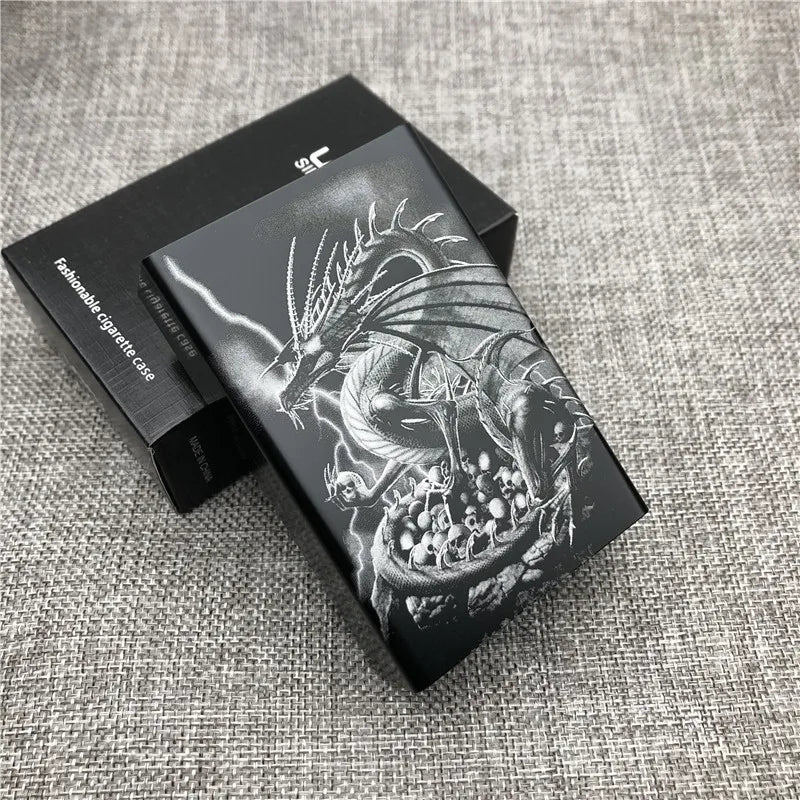 A black cigarette case with a custom engraved design of a dragon on the lid, resting on a gray fabric surface.