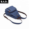 A dark blue canvas backpack with brown trim and straps shown from the side.