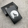 A black cigarette case with a silhouette of a wolf against a full moon is displayed on a gray fabric surface.