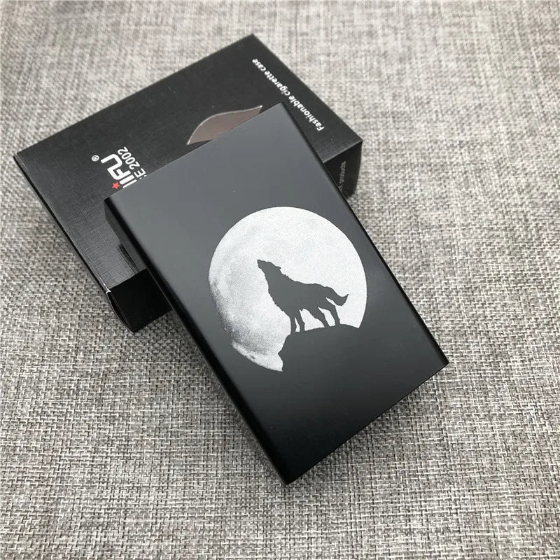 A black cigarette case with a silhouette of a wolf against a full moon is displayed on a gray fabric surface.