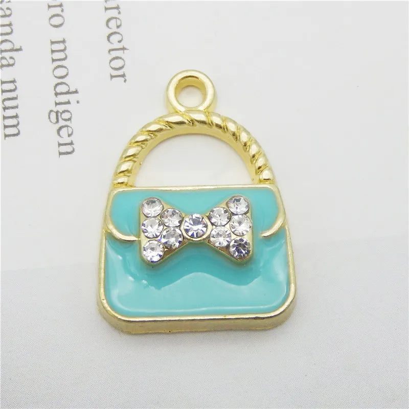Charm à sac ton or avec un nœud de cristal blanc sur fond émail bleu clair