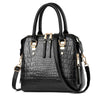 A black crocodile-embossed leather tassel shoulder bag with gold hardware.