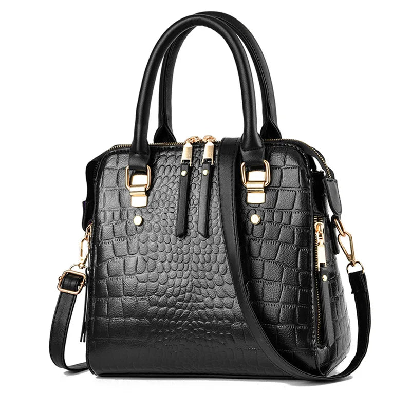 A black crocodile-embossed leather tassel shoulder bag with gold hardware.